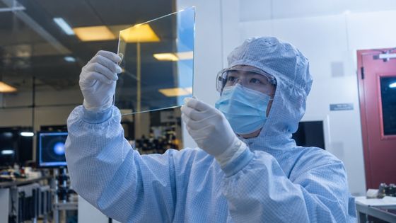 Technician inspecting a precision glass component during acceptance and delivery preparation